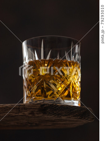 Crystal glass with ice cubes of scotch whiskey on top of wooden board and black. Crystal glass with ice cubes of scotch whiskey on top of wooden board and black. 79293010