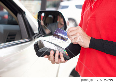 Gas station staff swipe mockup credit card via payment terminal after giving a price quote to the customer sitting in the car. Gas station staff swipe mockup credit card via payment terminal after giving a price quote to the customer sitting in the car. 79295799
