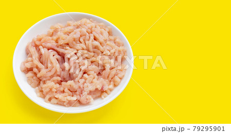 Minced meat of chicken fillet in white plate on yellow background. Minced meat of chicken fillet in white plate on yellow background. 79295901