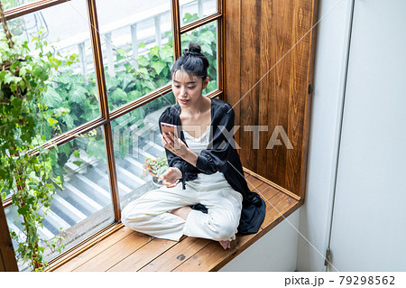 家でスマホを見る若い女性 79298562