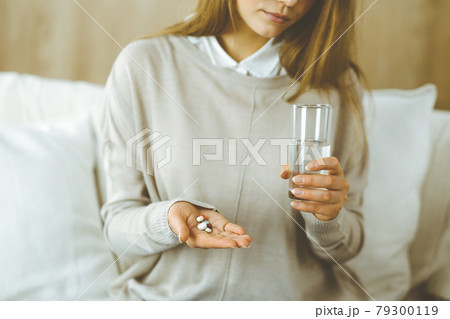 Close-up woman holding pills time to take medications, cure for headache, high blood pressure pain killer drugs at home. Stay at home concept during Coronavirus pandemic 79300119