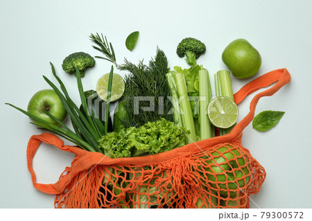 String bag with green vegetables on white background 79300572