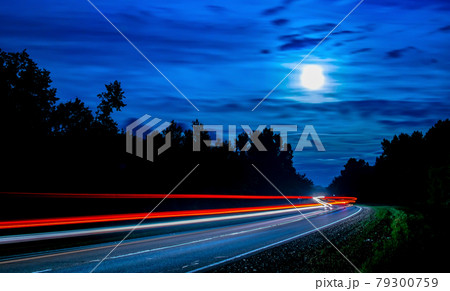 long lines of light from cars passing along the night forest long lines of light from cars passing along the night forest 79300759