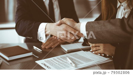 Unknown businessman shaking hands with his colleague or partner above the glass desk in modern office, close-up. Business people group at meeting 79302806