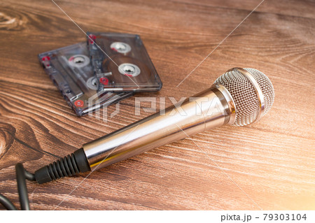 A silver analog microphone sits next to old cassette tapes 79303104