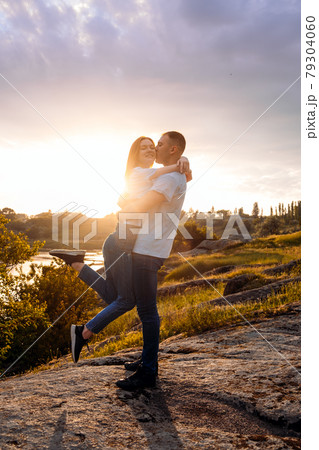 Romantic getaway, Romantic Destinations to Honeymoon, solo travel. Couple in love silhouette on nature sunset yellow and purple sky background. Young couple enjoying the sunset in the meadow. 79304060