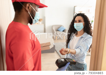 Black delivery man holding pizza box and pos terminal 79304865
