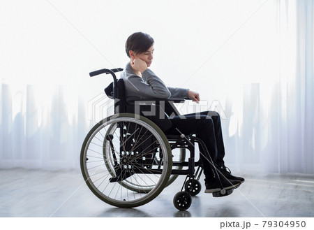 Stressed handicapped teenage boy in wheelchair feeling lonely and upset, sitting near window at home Stressed handicapped teenage boy in wheelchair feeling lonely and upset, sitting near window at home 79304950