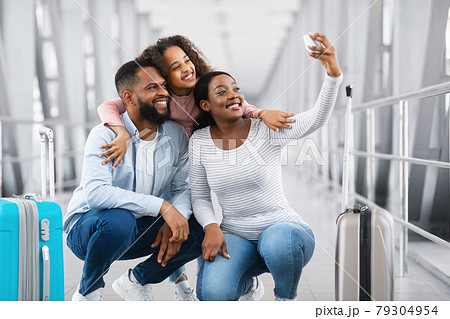 Black family traveling, taking selfie on cellphone in airport 79304954
