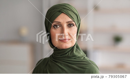 Middle-Aged Muslim Female Wearing Hijab Looking At Camera Posing Indoors 79305067