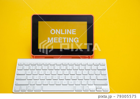 ONLINE MEETING text on digital tablet screen with wireless keyboard isolated on yellow background	 79305575