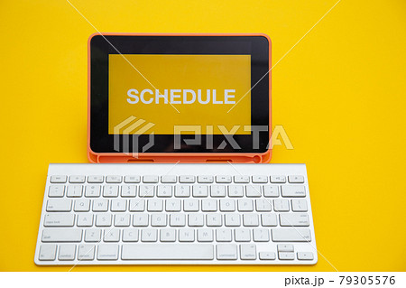 SCHEDULE text on digital tablet screen with wireless keyboard isolated on yellow background	 79305576