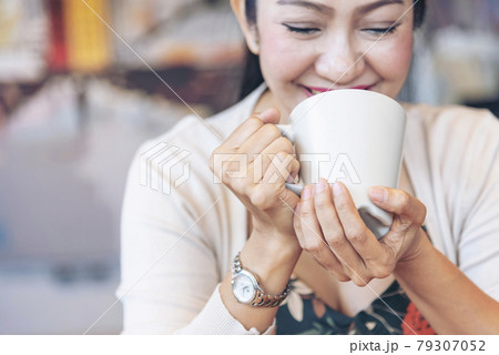 Woman holding coffee cup relaxing after work at office warm taste in cafe. Close up hands of woman sitting office desk holding sweet coffee cup relax and enjoy with happy time. Hot coffee mug in hand 79307052