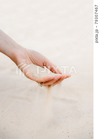 White sand pours through the fingers. White sand pours through the fingers. 79307467