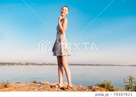 laughing teenager girl in a short haired dress stands on a cliff over a wide river laughing teenager girl in a short haired dress stands on a cliff over a wide river 79307621
