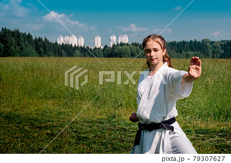 teen girl training karate kata outdoors, performing a strike oi zuki teen girl training karate kata outdoors, performing a strike oi zuki 79307627