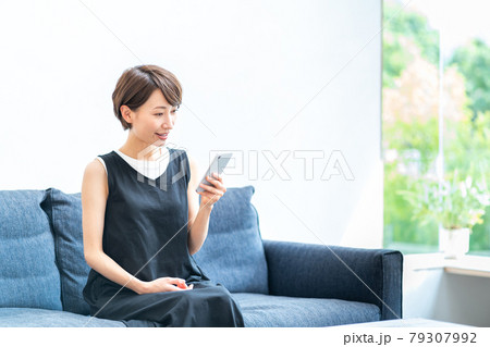 リビングでくつろぎながらスマホをするミドル女性。 79307992