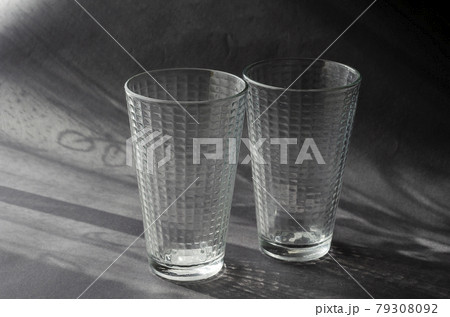 Two Empty Glasses on a gray surface with shadows. 79308092