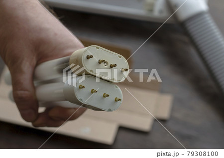 Adult Man's hand holds a burned-out and a new compact fluorescent bulb. Adult Man's hand holds a burned-out and a new compact fluorescent bulb. 79308100