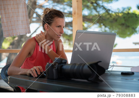 Young female photographer editing phots on her laptop 79308883