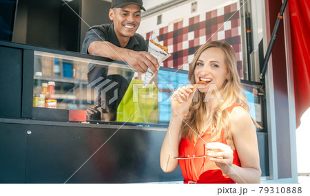 Beautiful woman ordering fries at a food truck 79310888