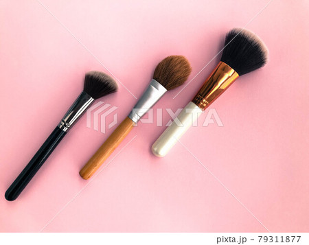 three tassels on a pink matte background. brushes for blush, powder, foundation and dry textures for contouring. face makeup. personal care, beauty and fashion 79311877
