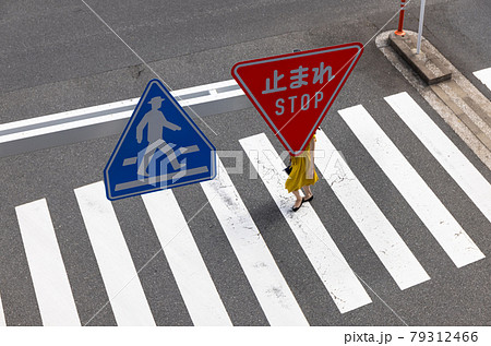 交差点の横断歩道を渡る女性と道路標識 交差点の横断歩道を渡る女性と道路標識 79312466