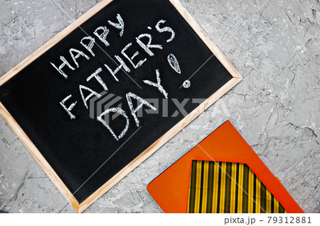 Happy fathers day on chalk board with orange diary and yellow tie on gray concrete background Happy fathers day on chalk board with orange diary and yellow tie on gray concrete background 79312881