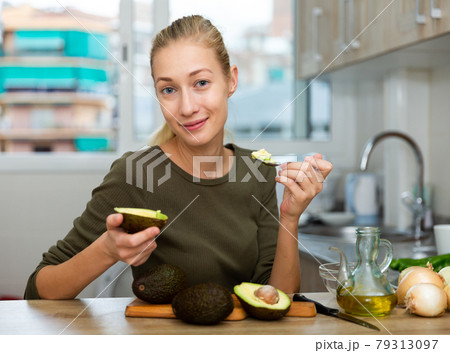 Portrait of girl with avocado in home kitchen Portrait of girl with avocado in home kitchen 79313097