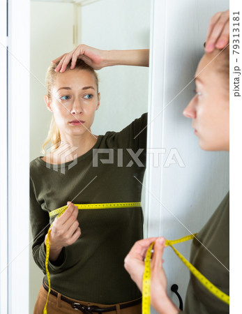 Woman measures breast volume in front of a mirror Woman measures breast volume in front of a mirror 79313181