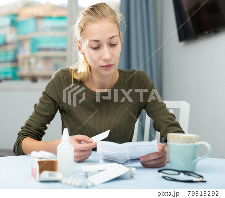 Sad young female reading recipe with pills 79313292