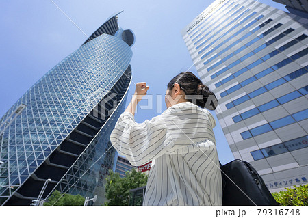高層ビル群を見上げながらカッツポーズしているビジネスウーマン 後ろ姿 高層ビル群を見上げながらカッツポーズしているビジネスウーマン 後ろ姿 79316748