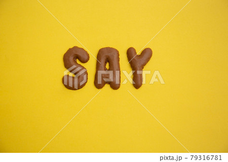 Word SAY arranged from homemade chocolate cookie alphabet on yellow table Word SAY arranged from homemade chocolate cookie alphabet on yellow table 79316781