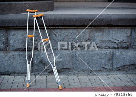 Pair of crutches for a man with an injury on the stairs. Pair of crutches for a man with an injury on the stairs. 79318369