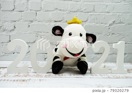 2021 Happy New Year and Cute Funny cow doll with space copy on white brick wall and wooden background 2021 Happy New Year and Cute Funny cow doll with space copy on white brick wall and wooden background 79320279
