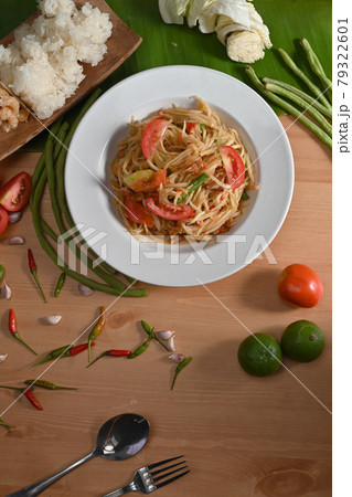 Spicy green papaya salad in white plate on wooden table. Spicy green papaya salad in white plate on wooden table. 79322601