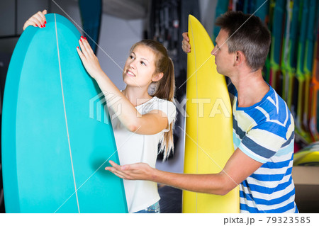 couple is demonstraiting surfboard in nautical shop. 79323585