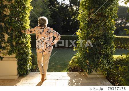 Senior caucasian woman leaning on column in sunny garden Senior caucasian woman leaning on column in sunny garden 79327178