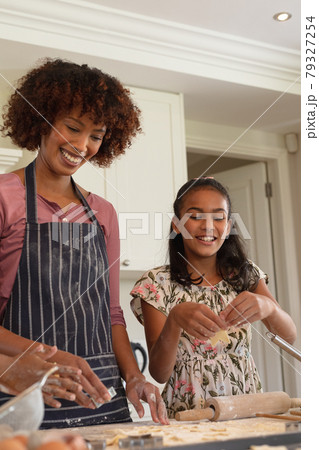 Happy african american mother with daughter baking in kitchen, cutting cookies 79327254