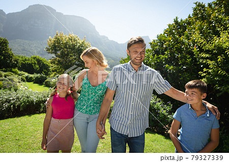 Happy caucasian couple with daughter and son outdoors, walking in sunny garden 79327339