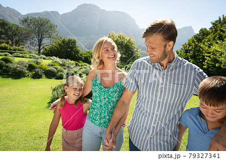 Happy caucasian couple with daughter and son outdoors, walking in sunny garden 79327341