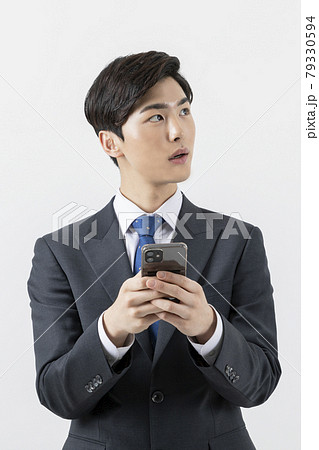 Asian man businessman holding smartphone, looking at side Asian man businessman holding smartphone, looking at side 79330594