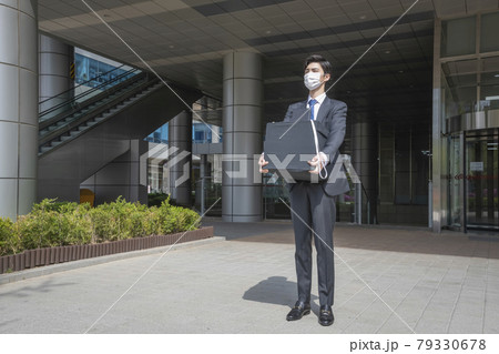 Asian man employee with mask leaving office with box due to lay off, covid 19 effects in business Asian man employee with mask leaving office with box due to lay off, covid 19 effects in business 79330678