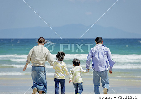 海辺で遊ぶ4人家族の後ろ姿の写真素材