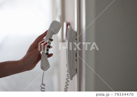 Woman hand picking up phone in hotel corridor closeup 79334470