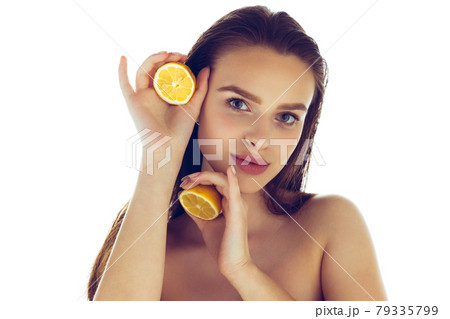 Portrait of beautiful young caucasian girl posing at camera with half of lemon isolated on gray studio background. Portrait of beautiful young caucasian girl posing at camera with half of lemon isolated on gray studio background. 79335799