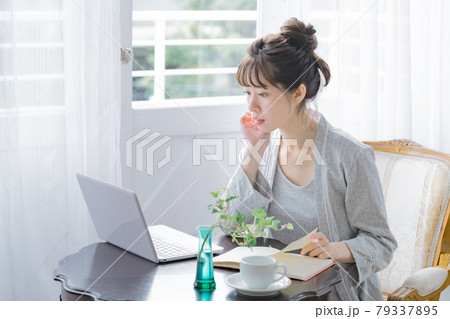 部屋着でパソコンとノートでスケジュールを確認する若い女性 部屋着でパソコンとノートでスケジュールを確認する若い女性 79337895