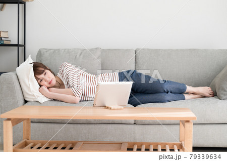 ソファーに寝ながらタブレット端末を見る女性 ソファーに寝ながらタブレット端末を見る女性 79339634