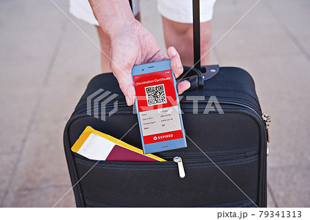 Open suitcase and smartphone in hand displaying on app mobile expired digital vaccination certificate for Covid-19. Immunity vaccine passport, vaccination certificate, health passport for travel 79341313