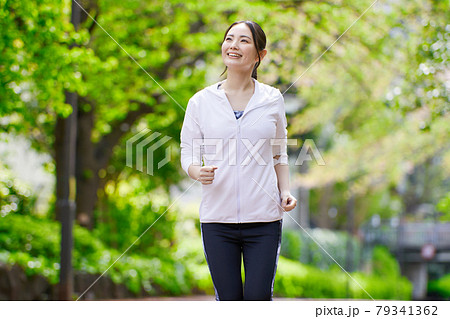 笑顔でジョギングする若い女性 笑顔でジョギングする若い女性 79341362